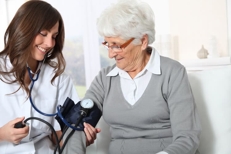 Nurse checking senior woman’s blood pressure.