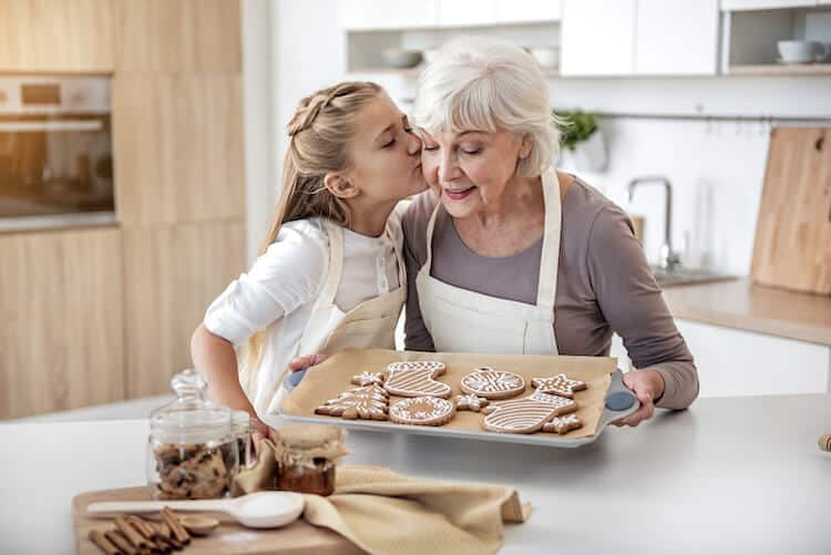 Senior grandmother baking cookies with granddaughter.