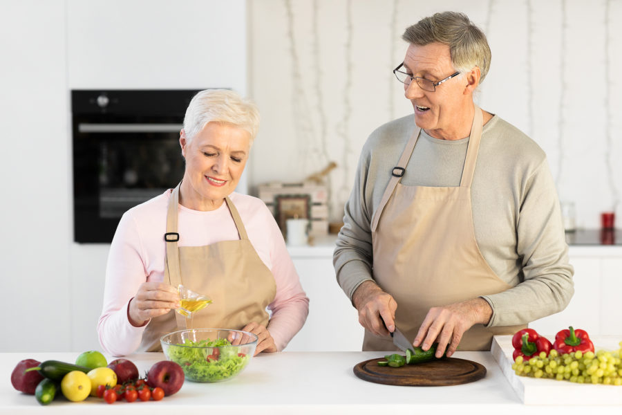 A senior couple enjoy cooking new dishes as an indoor hobby in their kitchen