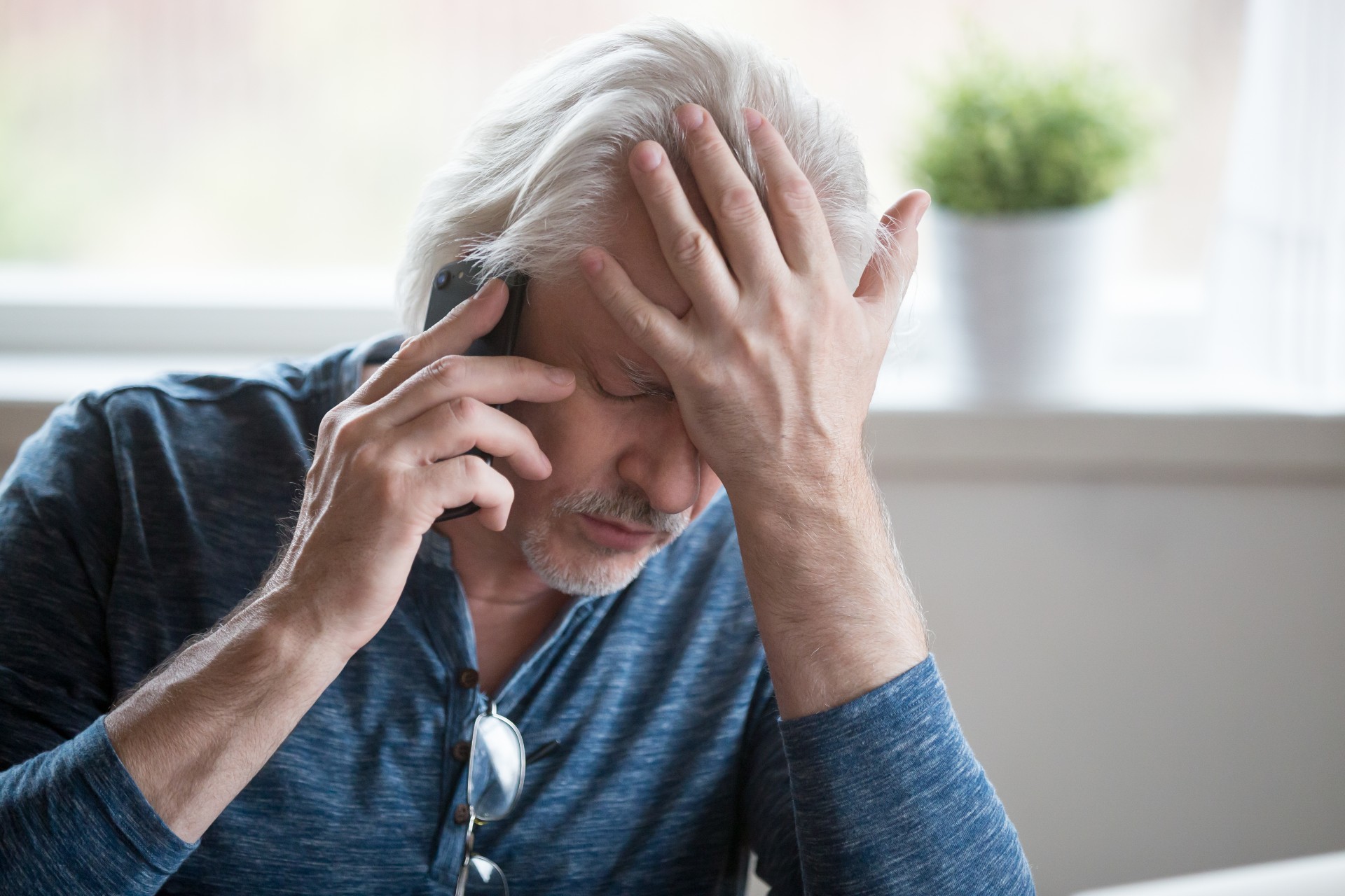 Frustrated senior man on the phone hearing bad news