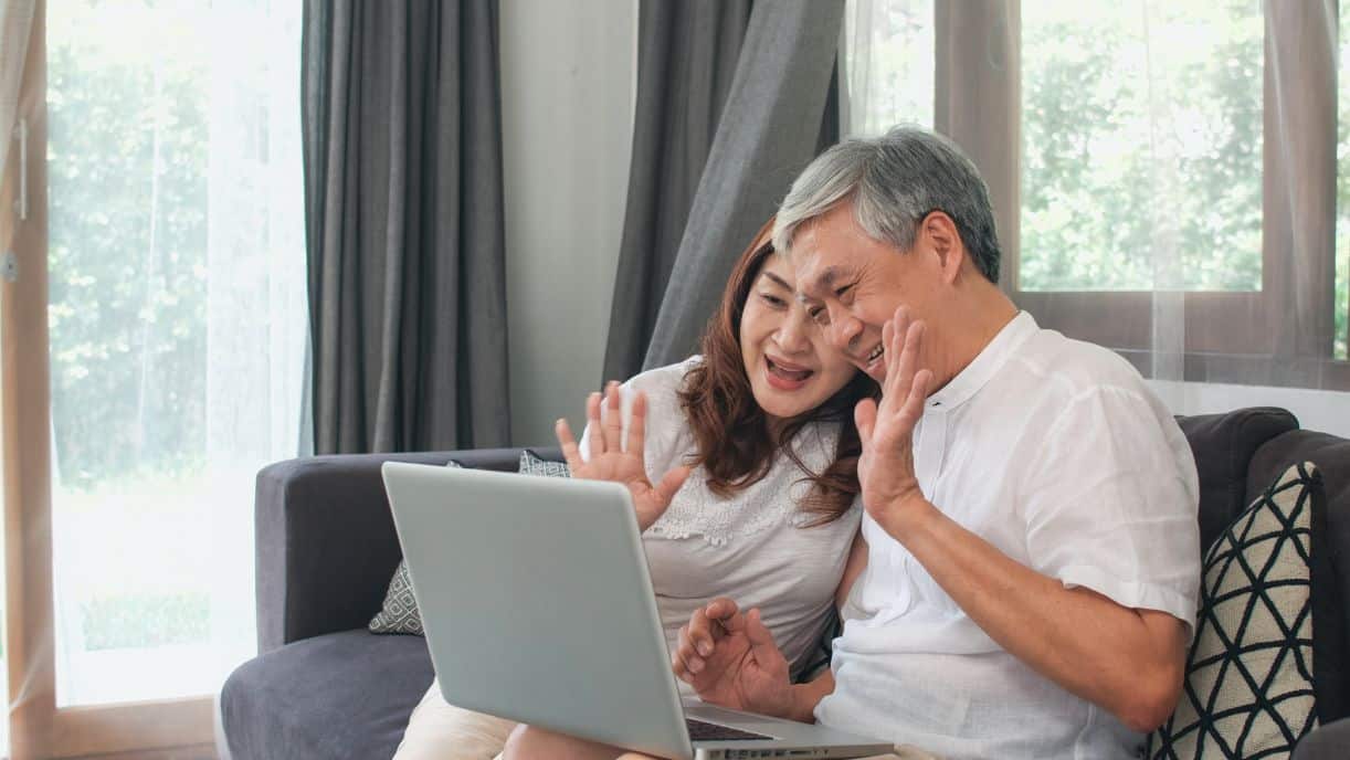 A senior couple talk to their family through a video call on their computer.