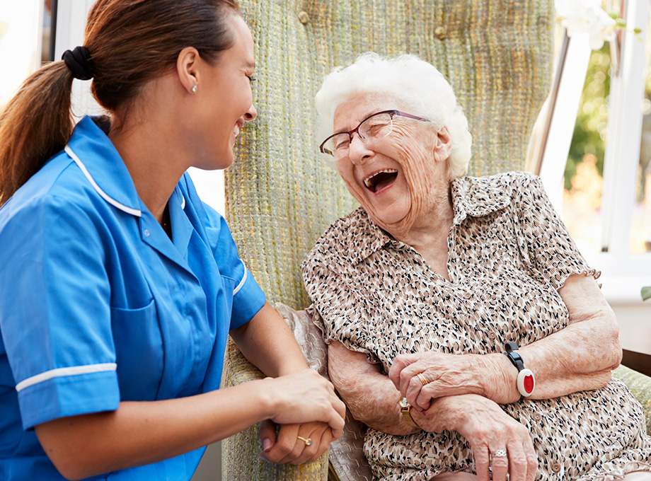 provider laughing with senior woman in wheelchair