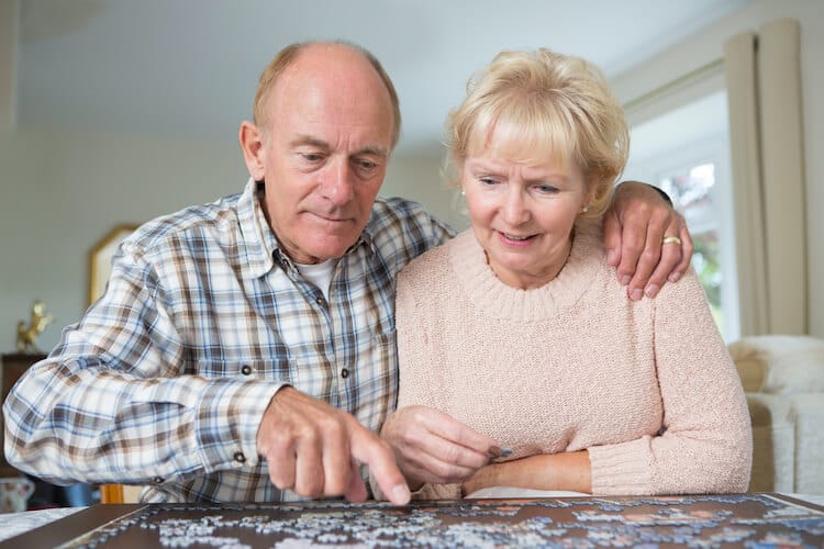 Senior couple keeping their brain healthy by completing a puzzle.