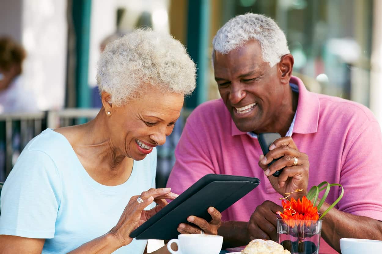 Senior couple using tablet at restaurant dinner table