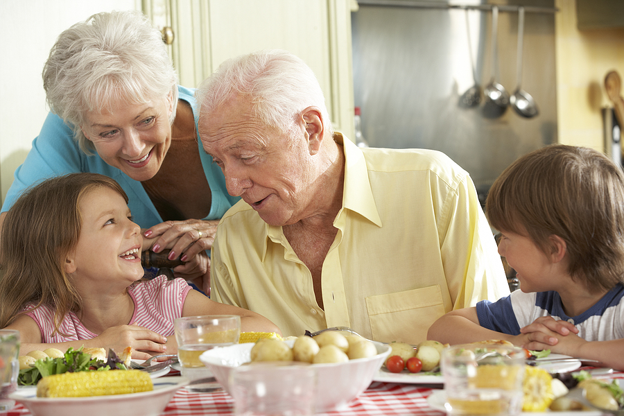 Grandparents sitting at the kitchen table, smiling with their grandchildren
