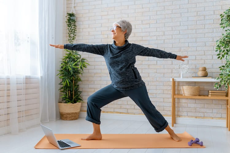 Senior woman participating in an online balance exercise class as a way to stay active while at home.