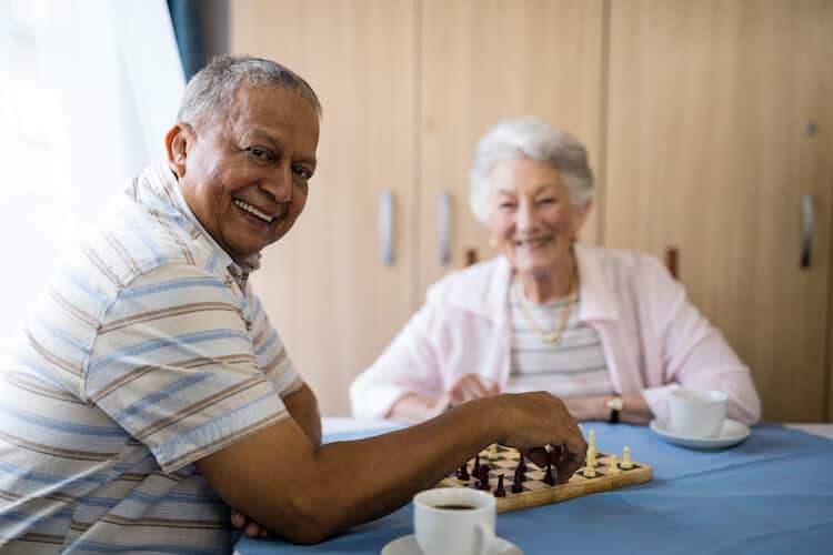 Two senior friends playing a board game indoors.