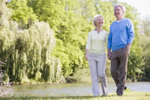 Senior couple enjoying a walk by a pond.