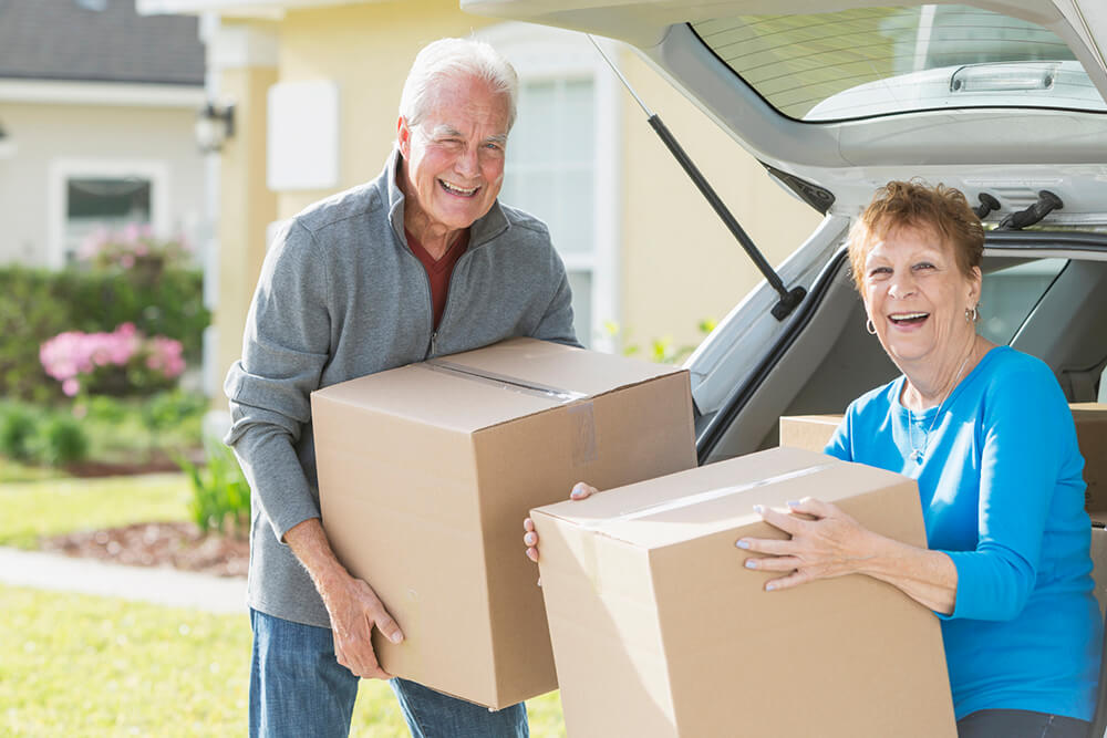 elderly couple carrying boxes of their belongings