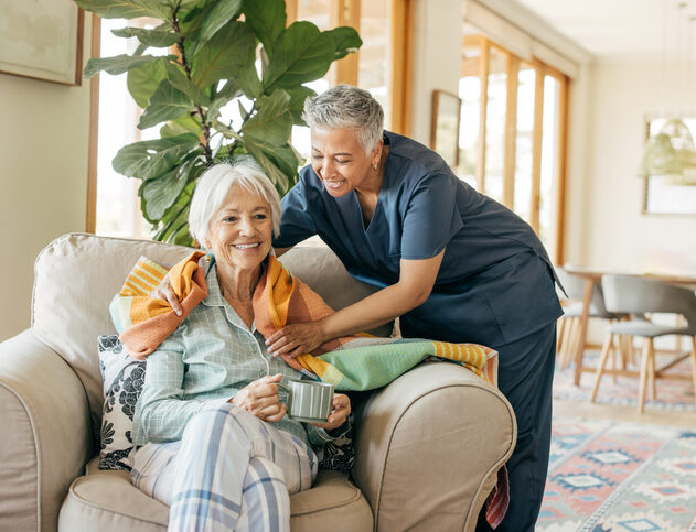 Senior getting wrapped in blanket by care giver