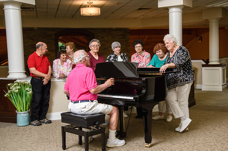 Seniors listening to friend playing piano