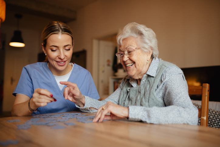 Senior completing puzzle with caregiver