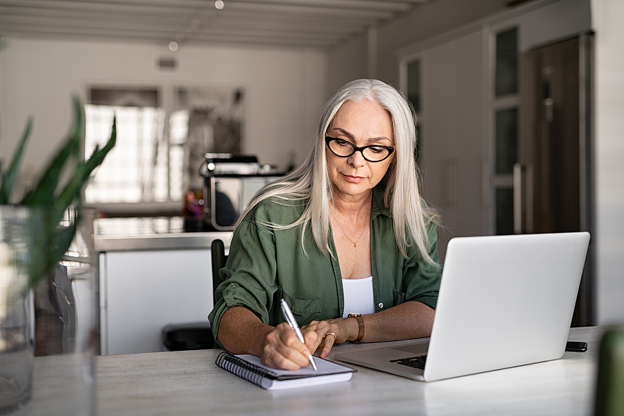 A senior woman works on her laptop.