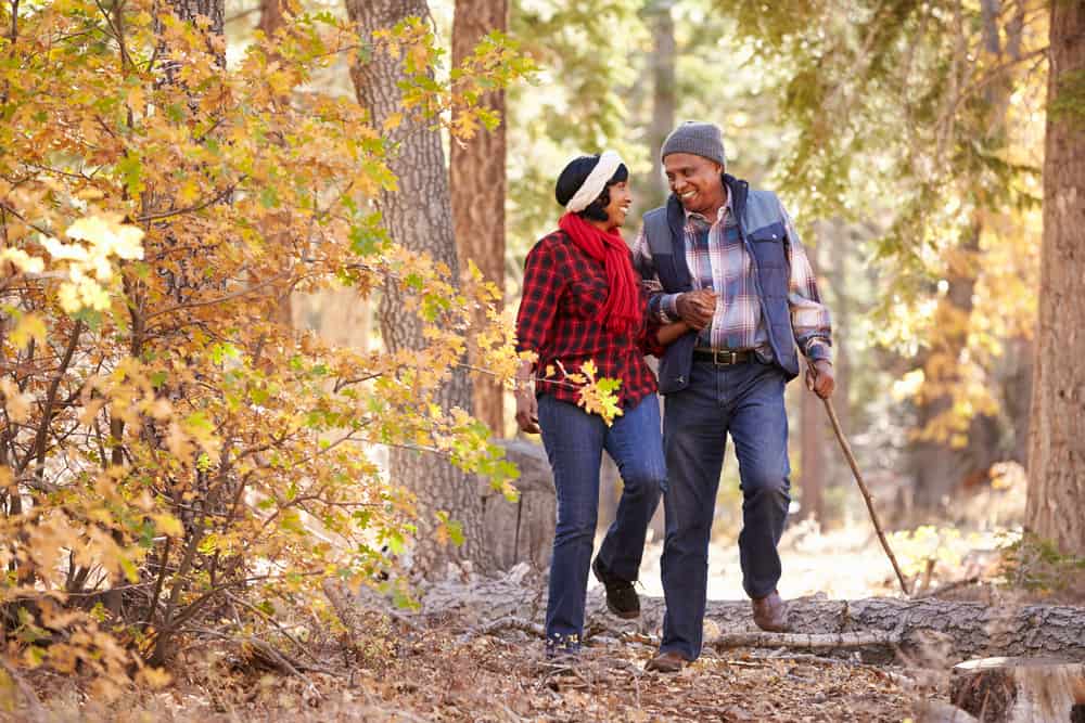 Two seniors walking through the forest in autumn