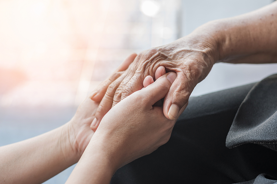 Older adult and adult child hold hands while discussing memory care
