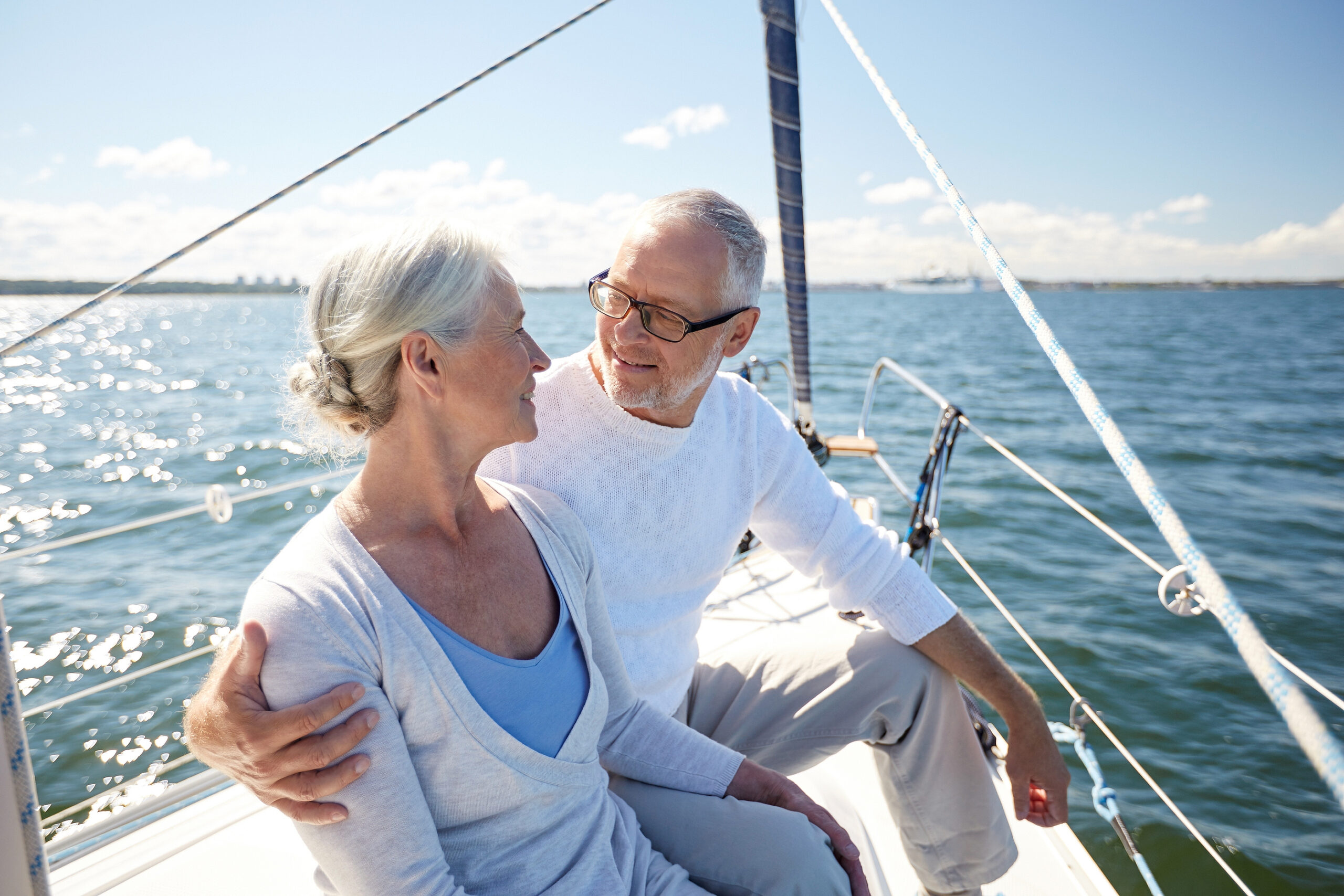 An older adult couple looks at each other while sailing