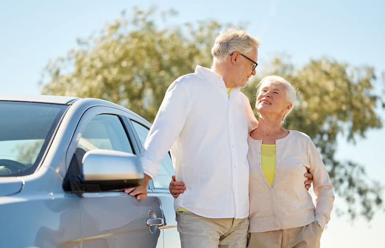 Senior couple standing near their car.