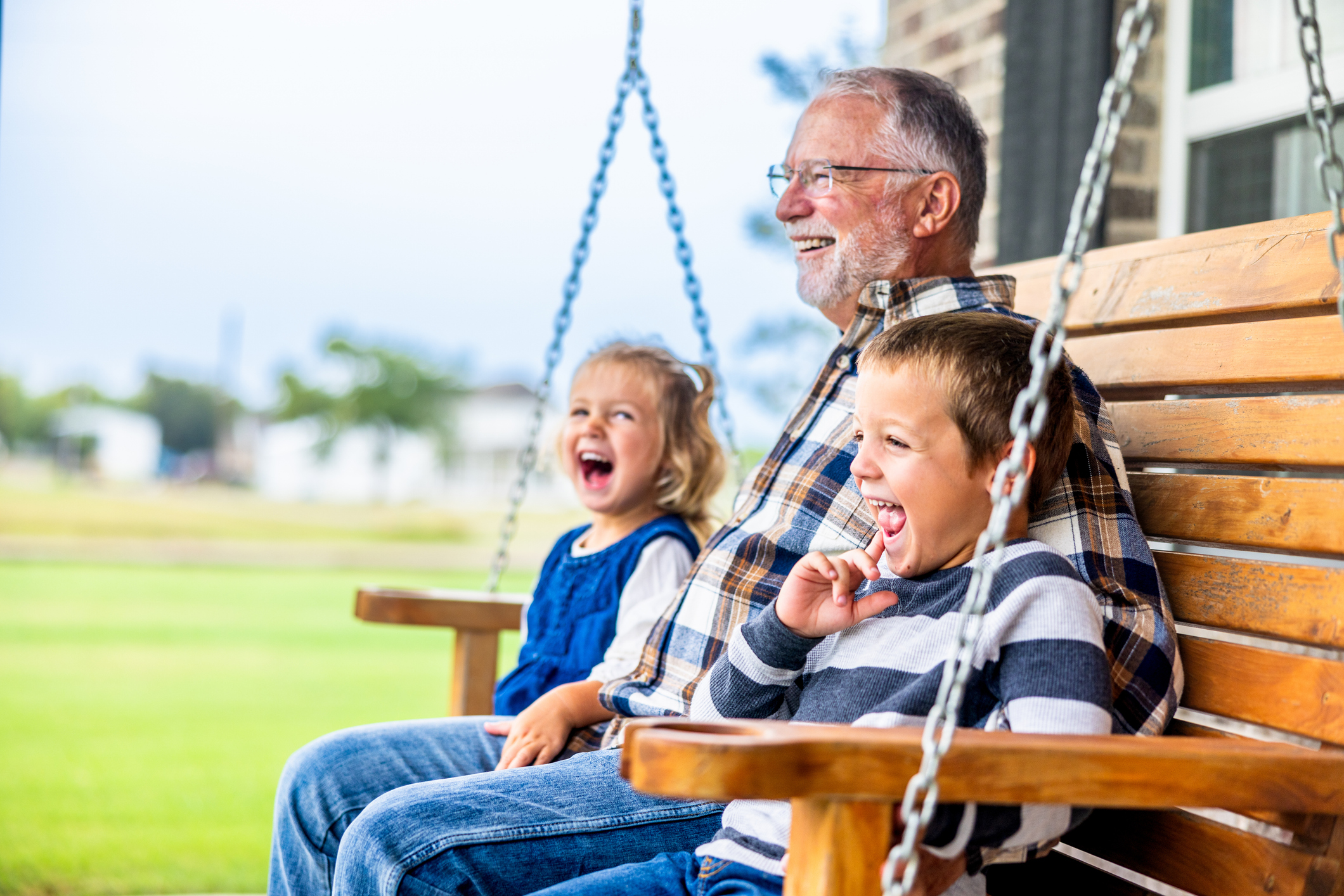 Senior man with two grandkids sitting on an outdoor porch swing