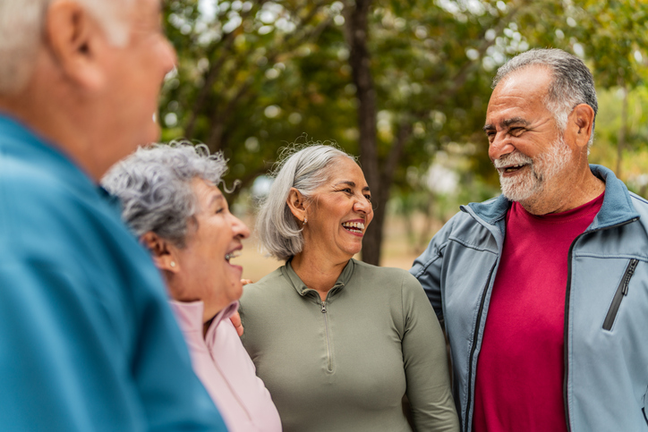 A group of senior couples stand together laughing